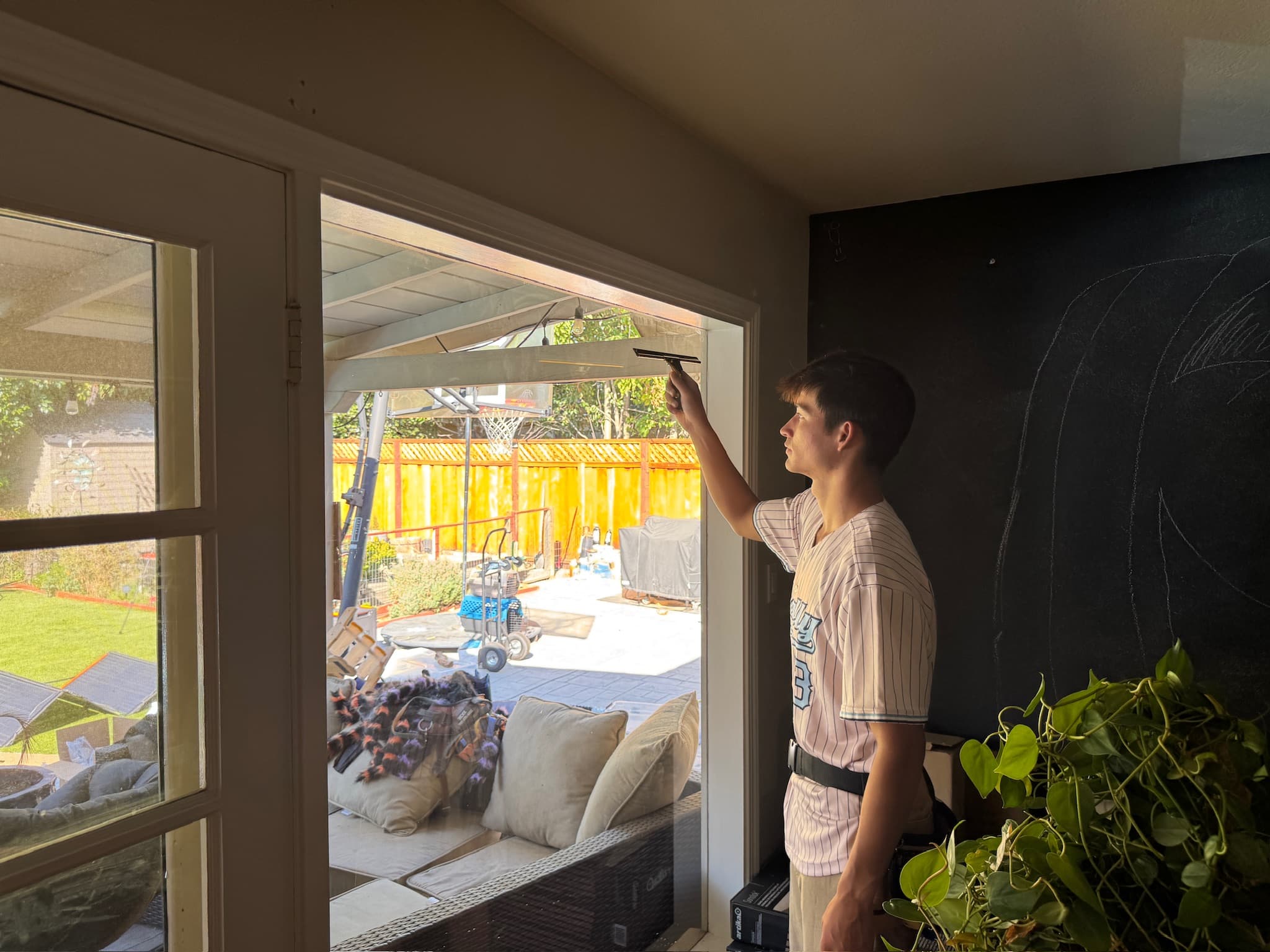 A Rally cleaner squeegeeing the inside of a large window from within a room.